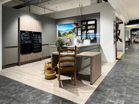 Kücheninsel im Fokus mit Holzelementen und Hängeleuchten, daneben Essbereich mit stilvoller Beleuchtung und Dekoration.