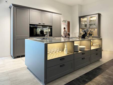 Moderne Küche in Grau mit Glasvitrinen und einer zentralen Insel, umgeben von Edelstahlgeräten.