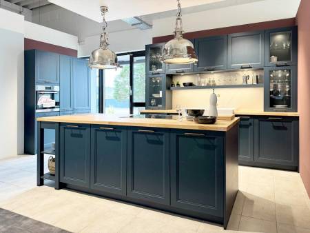 Elegante dunkelblaue Küchenzeile mit Holzarbeitsplatte und großen Pendelleuchten über der Insel.