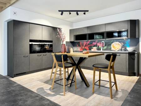 Küche mit dunkelgrauen Schränken, goldfarbenen Griffen, und einer auffälligen, farbenfrohen Rückwand.