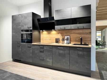 : Zeitgenössische Küche mit dunkelgrauen Fronten und einer Arbeitsplatte im Betonlook, ausgestattet mit modernen Einbaugeräten und einer beleuchteten Holzrückwand, vor einem hellen Holzboden.