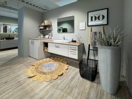 Stilvolles Badezimmer mit Holzakzenten, weißem Waschtisch und runder dekorativer Matte.