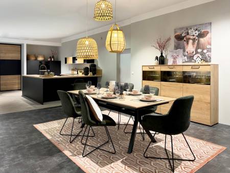 Moderne Esszimmereinrichtung mit schwarzen Stühlen, Holztisch und Pendelleuchten, neben einer Küche mit Holzschränken und einer Kuh-Kunstwanddekoration.